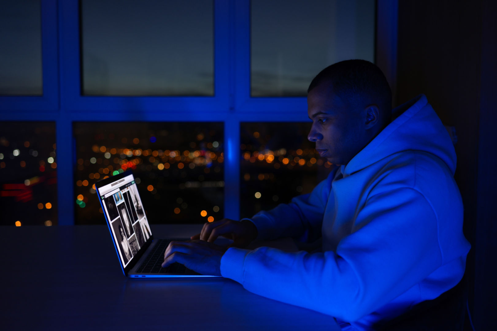 A black man on his laptop working at night.