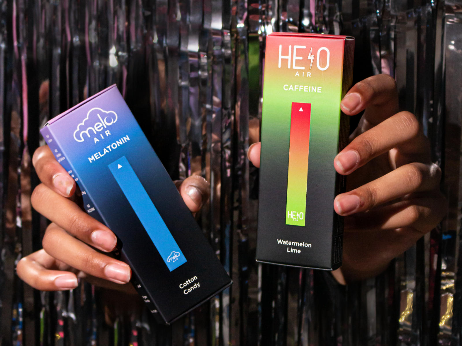 Person holding boxes of MELO Air Melatonin Diffuser in Cotton Candy and Helo Air caffeine diffuser in Watermelon Lime flavors.