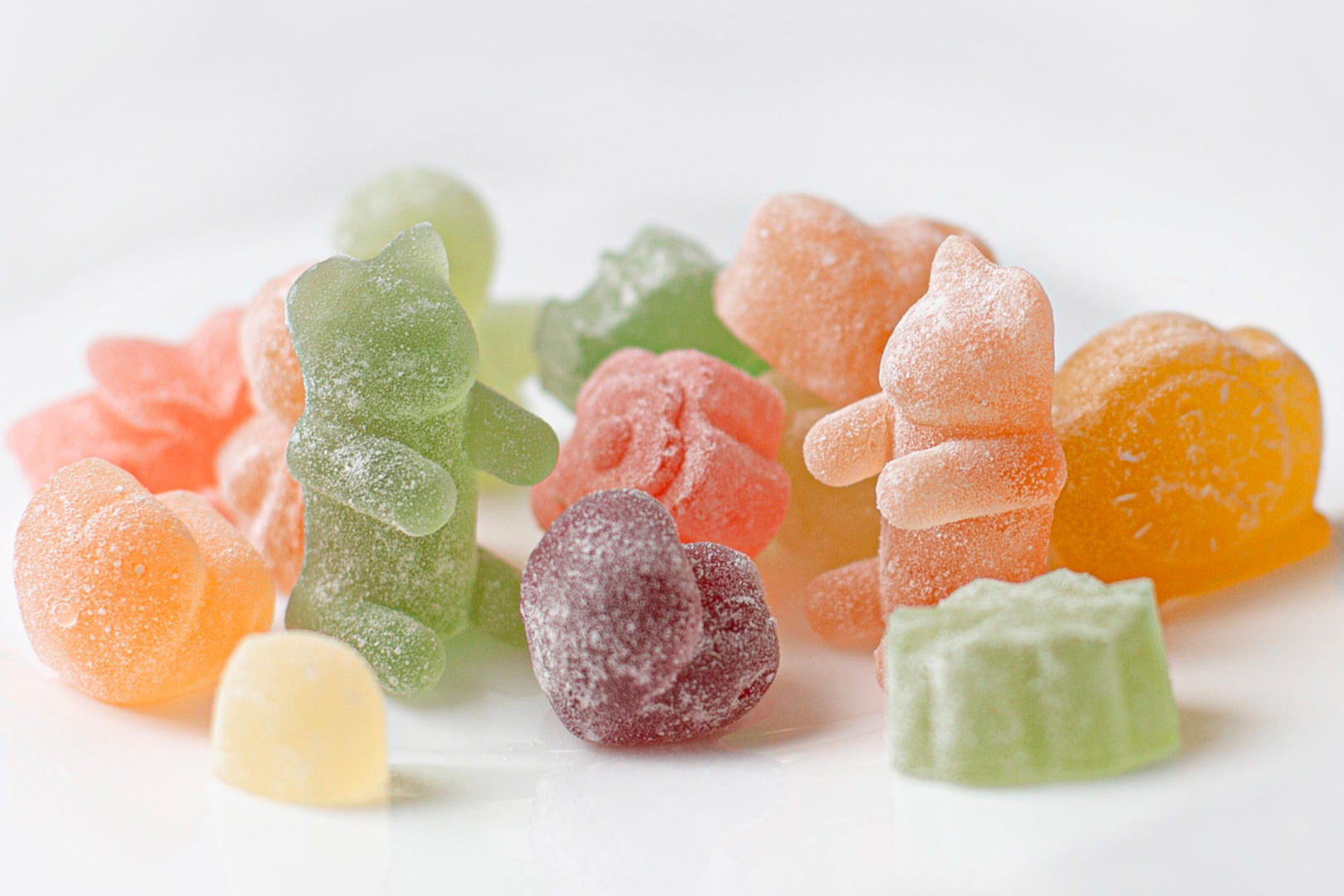 A handful of different colored gummies in a white surface