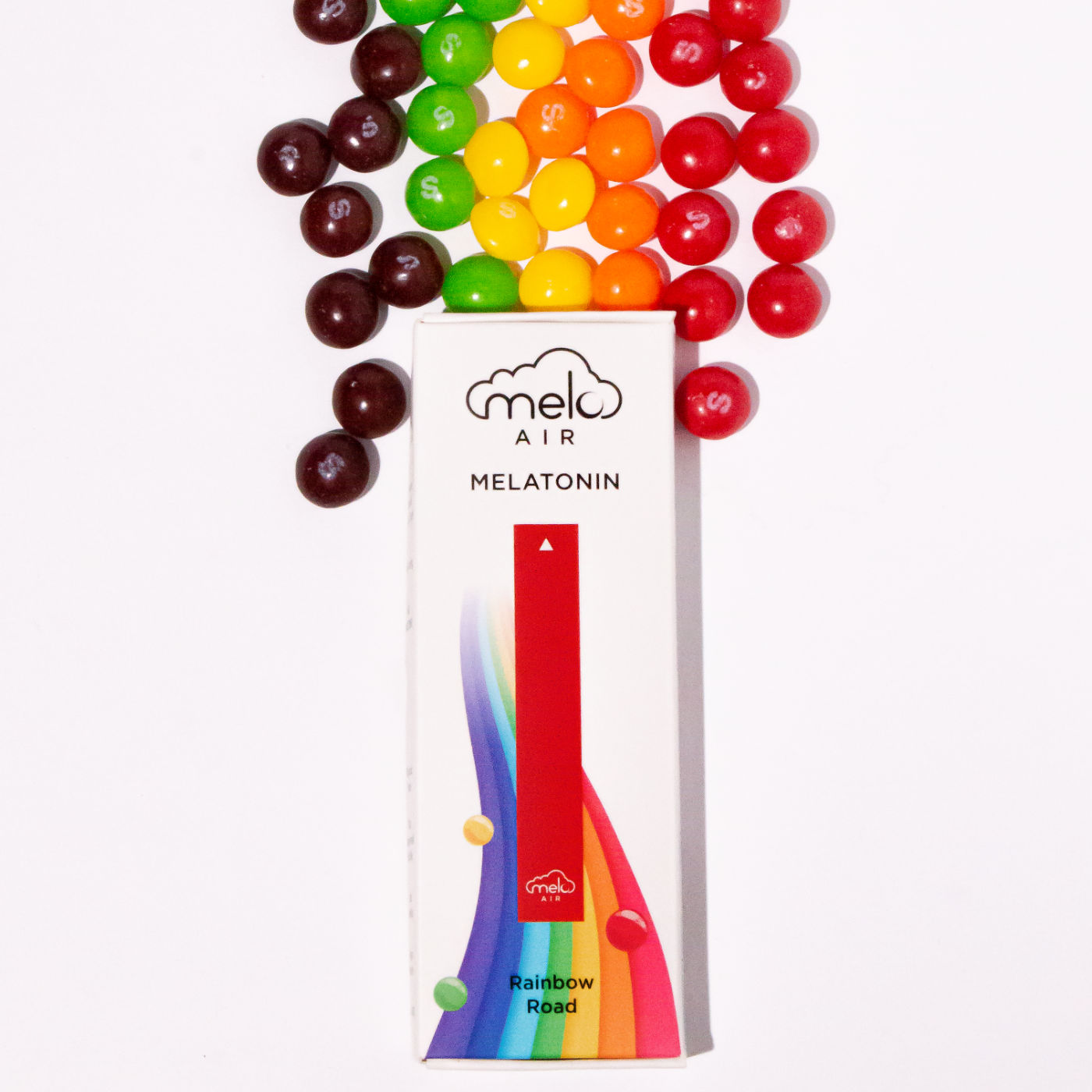 A box of Melo Air Melatonin Vaporizer in Rainbow Road flavor with a line of rainbow-colored candies behind.