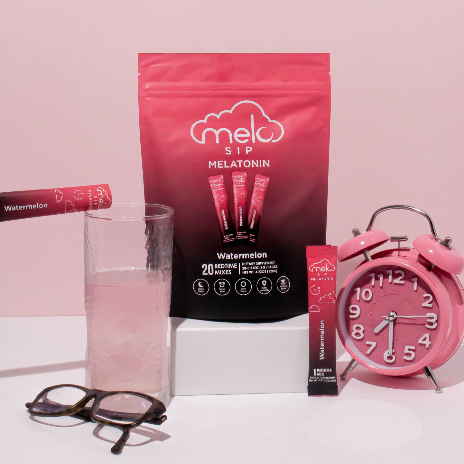 A pack of MELO Sip melatonin powdered drink in watermelon flavor poured into a glass of water