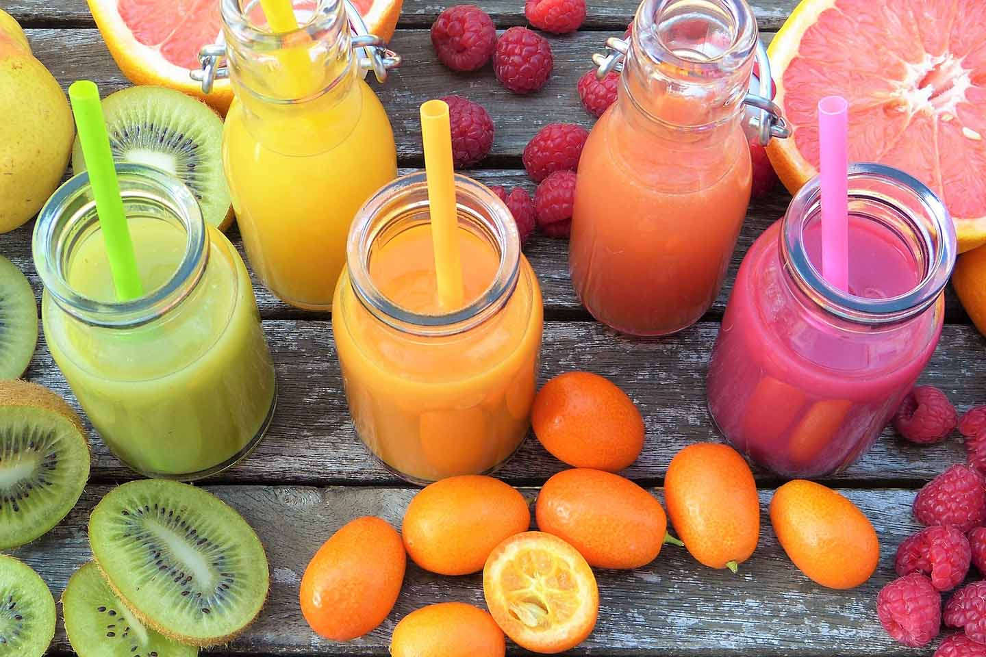 five bottles of juice with assorted fruits on table