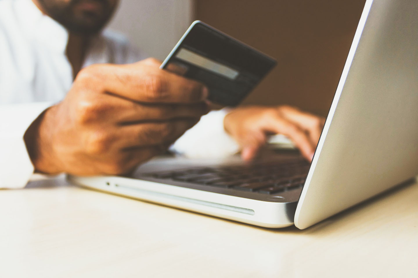 a person using laptop computer while holding a credit card